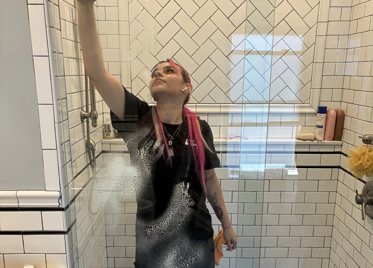 Deep cleaning service — cleaner scrubbing shower tile and glass