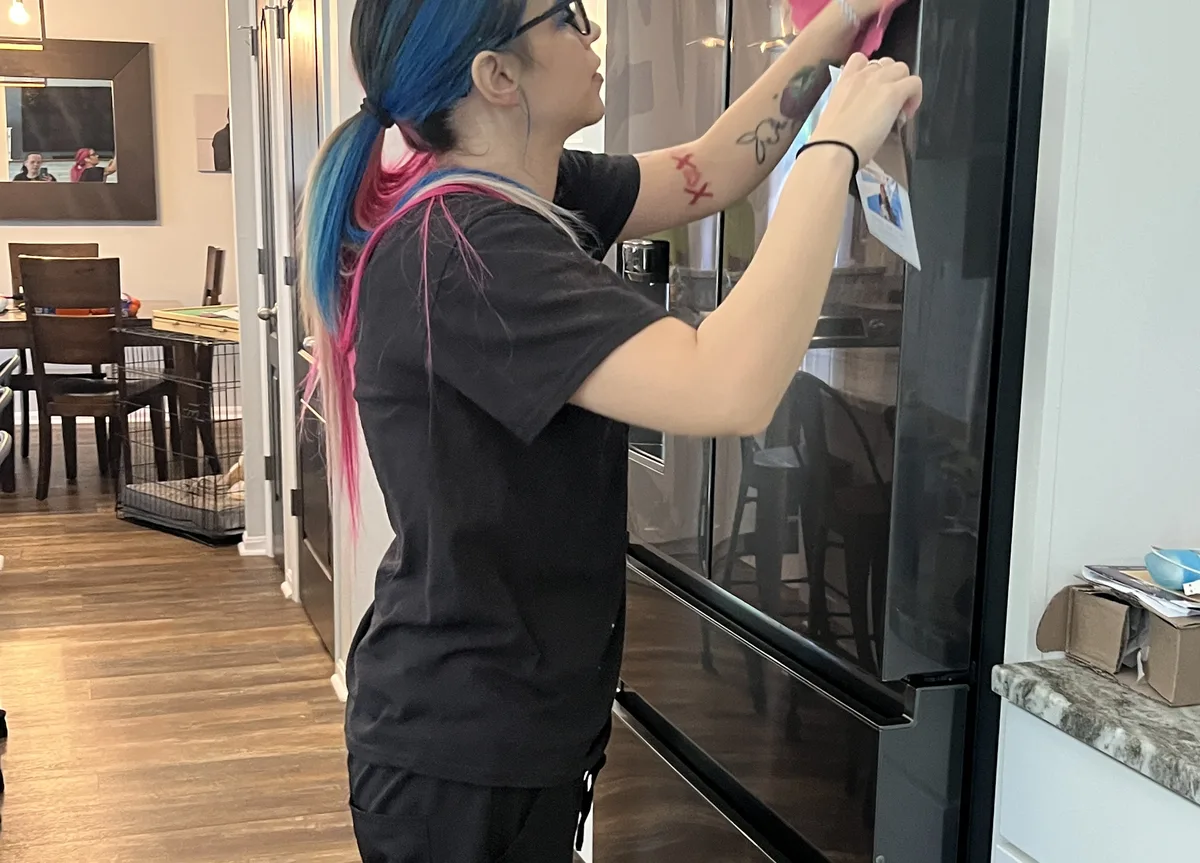 Recurring house cleaning service — cleaner polishing a kitchen refrigerator