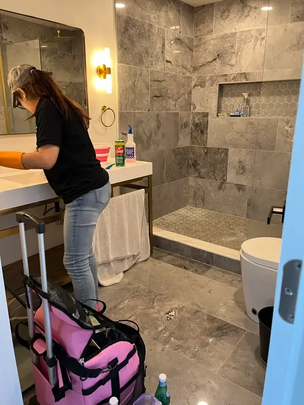 Cleaner wiping down a bathroom vanity during a move-out clean
