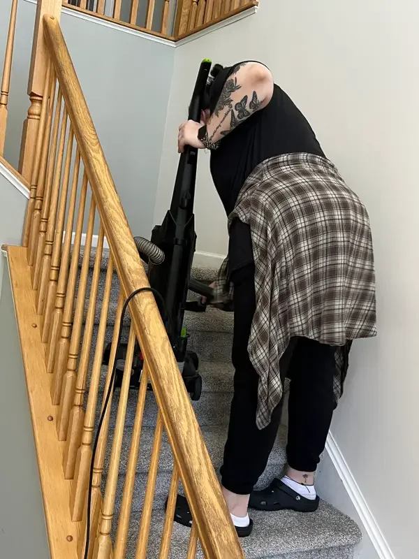 Cleaner vacuuming carpeted stairs on a recurring cleaning visit